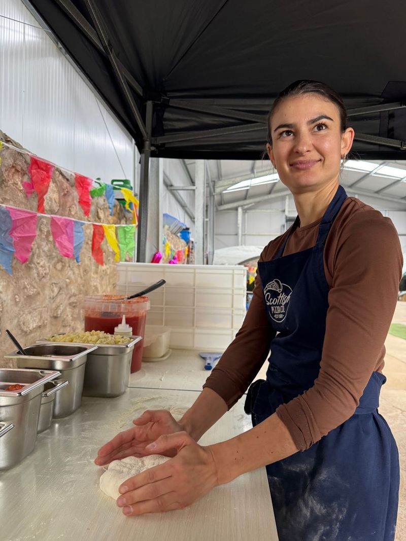 Smiling Scottish Pizza Co chef in a branded apron at the pop-up pizza counter
