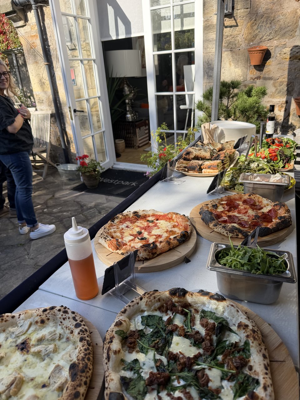 Freshly cooked pizzas, salads and sides laid out for guests on a sunny terrace