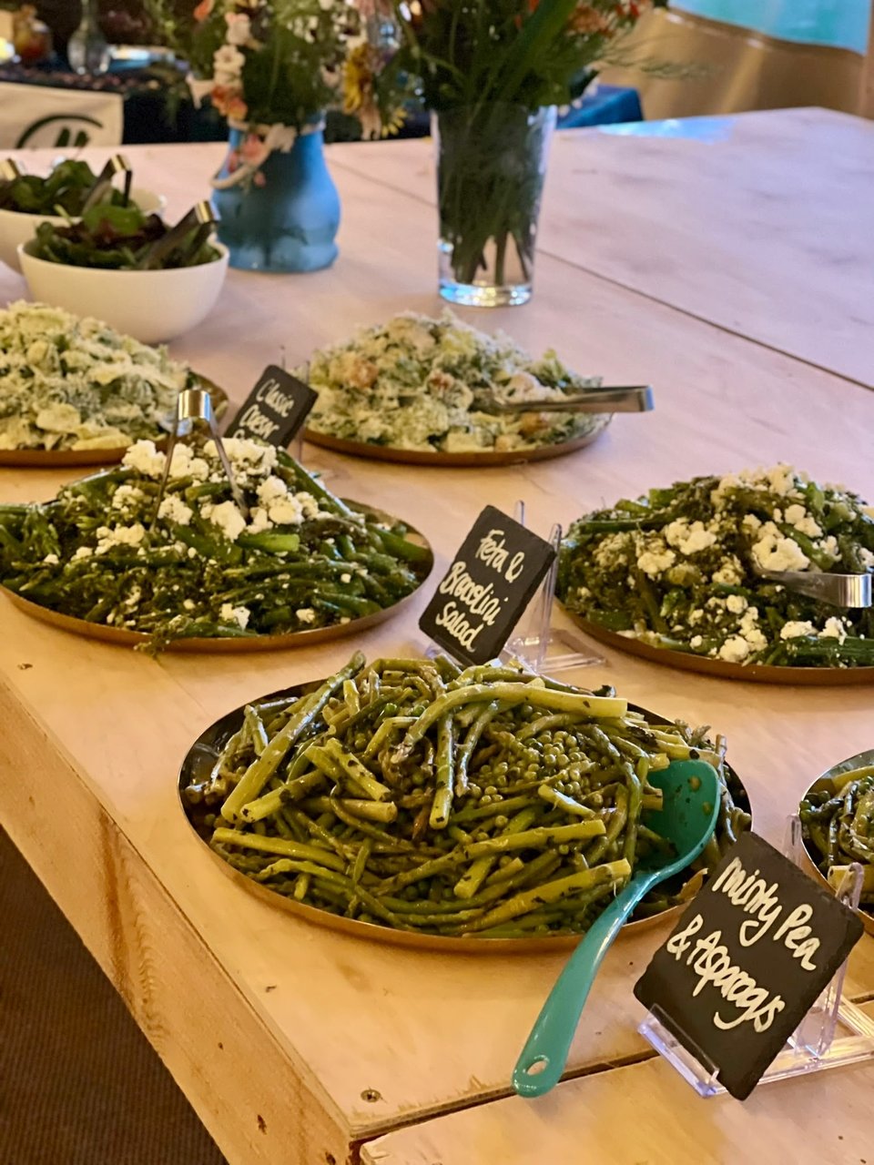 Wedding salad buffet with green beans, broccolini and chalkboard labels in a marquee